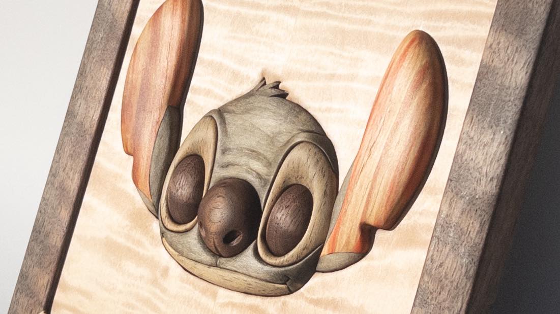 Close-up of dimensional hand-carved character relief showing sculpted depth and wood figure